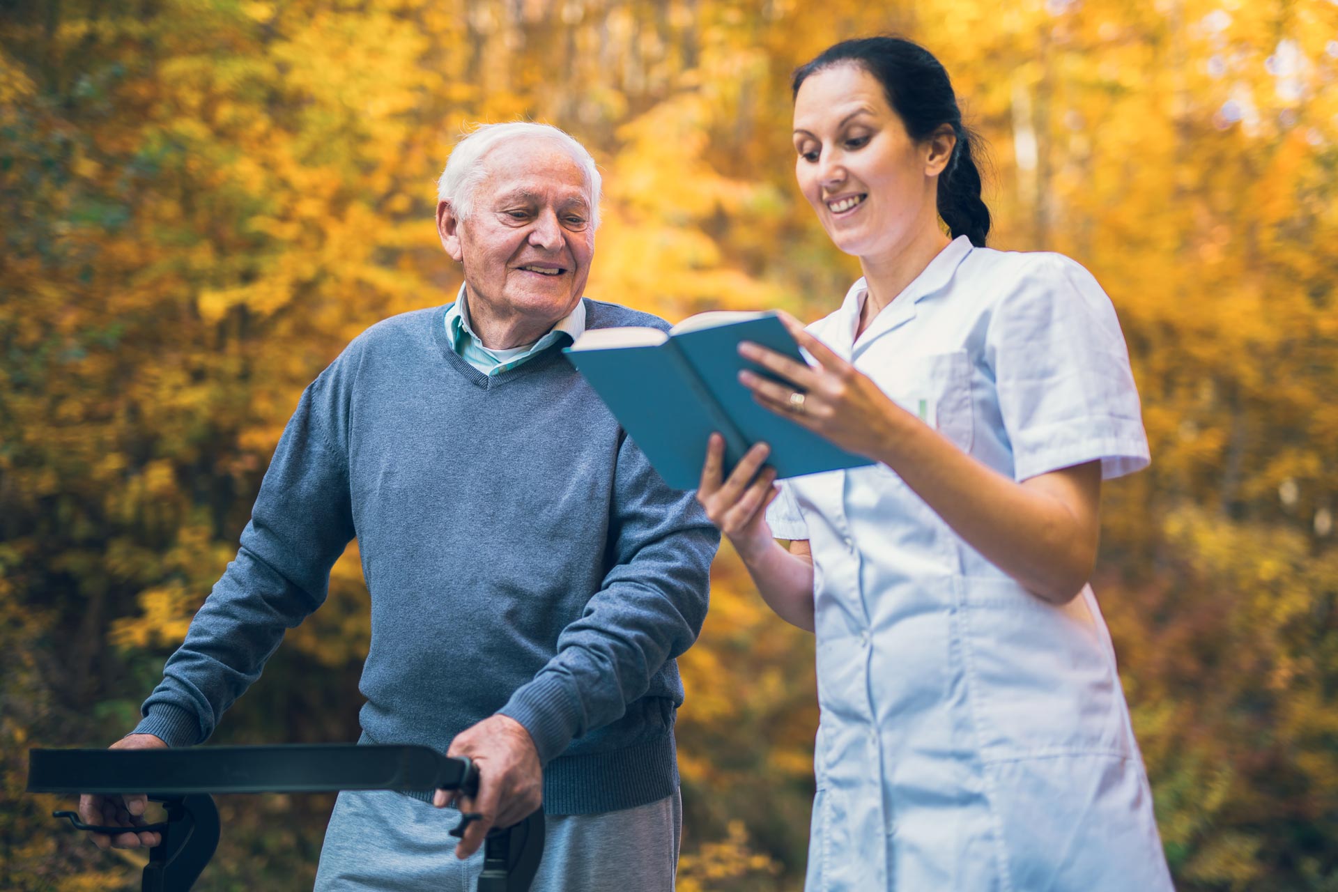nurse reading book to elderly man